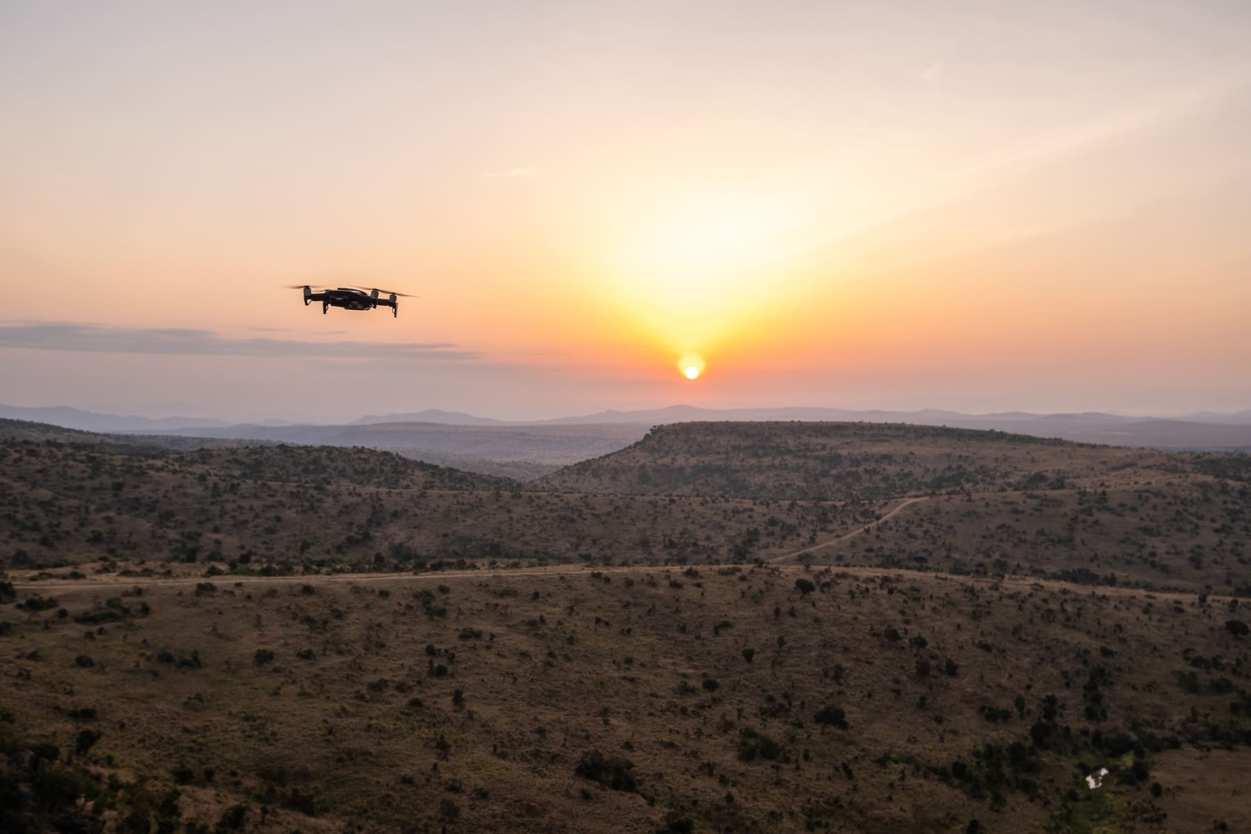 A drone flying over African hills at sunset